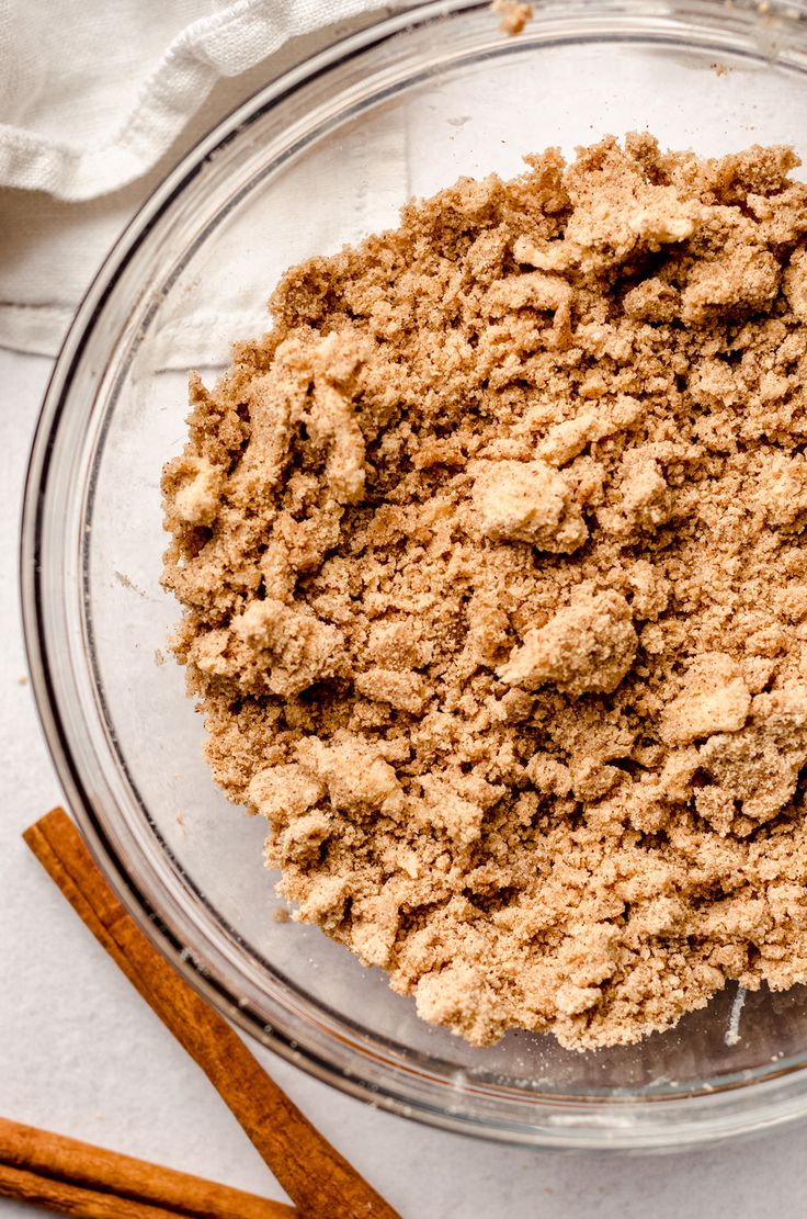 cinnamon sugar in a glass bowl next to cinnamon sticks