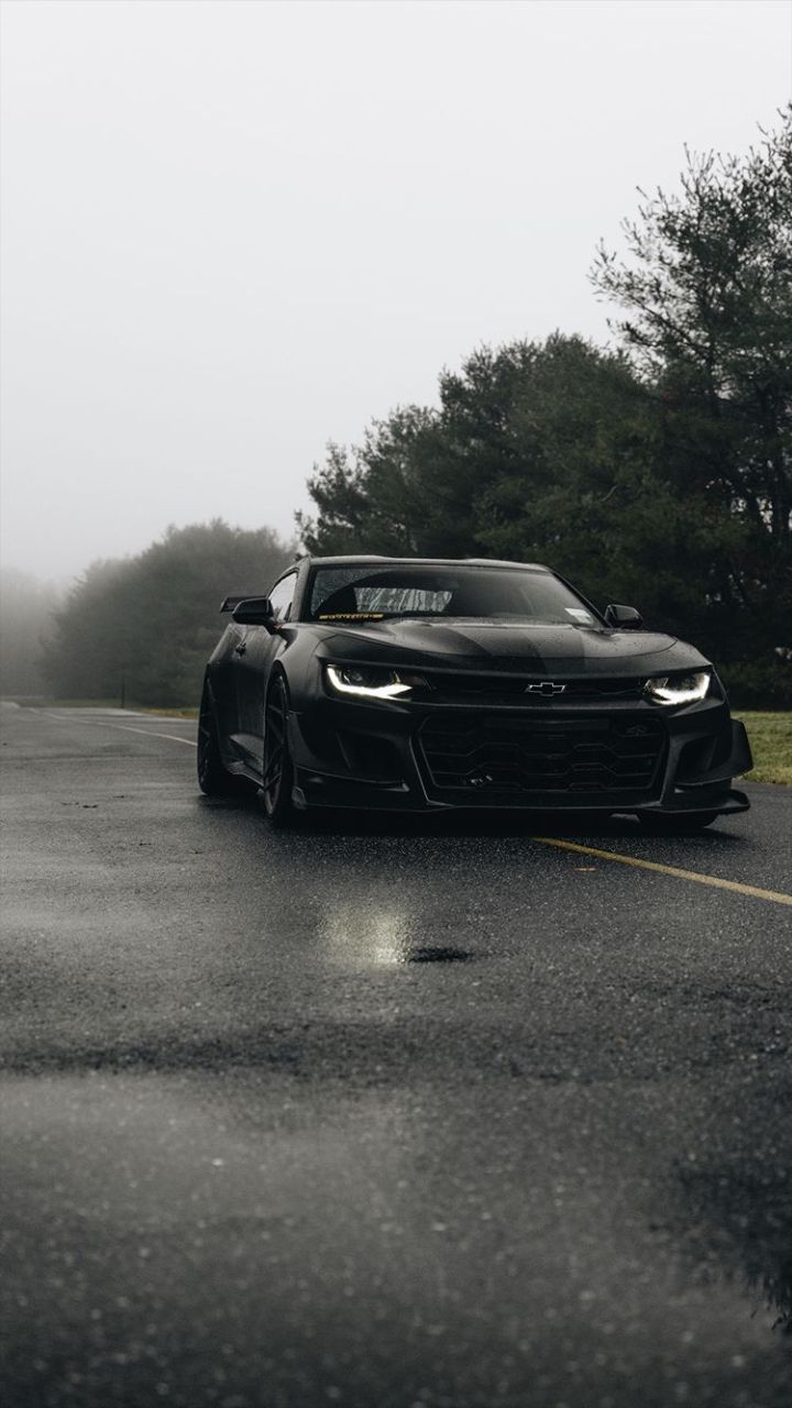 a black sports car driving down a wet road