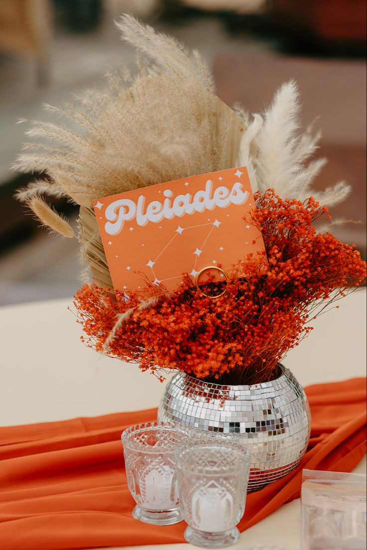 a silver vase filled with lots of orange and white flowers on top of a table