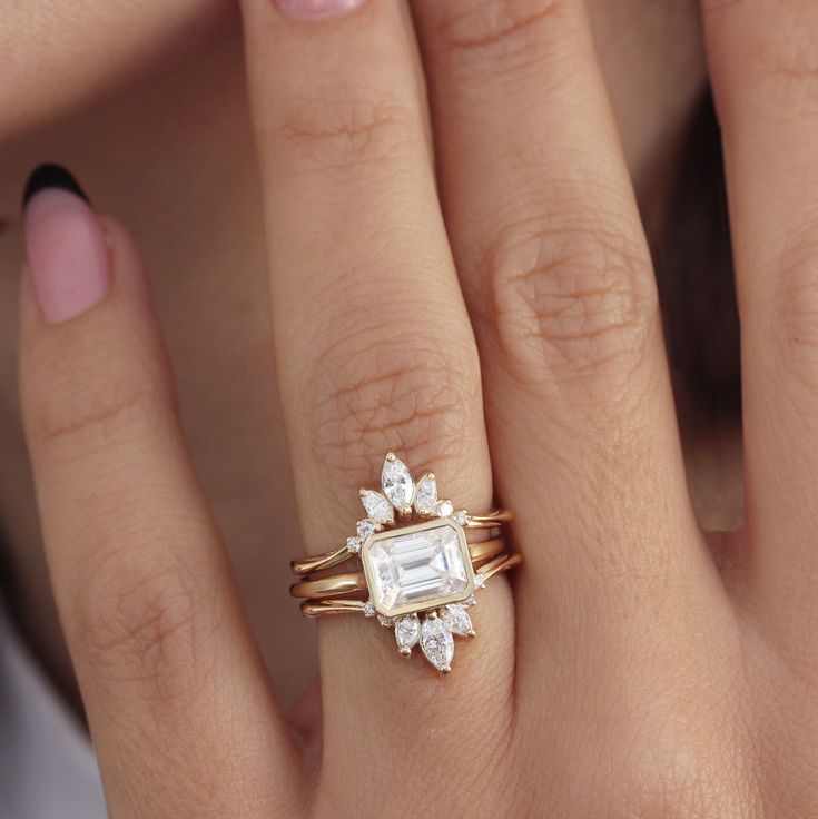 a woman's hand with two rings and an engagement ring on top of her finger