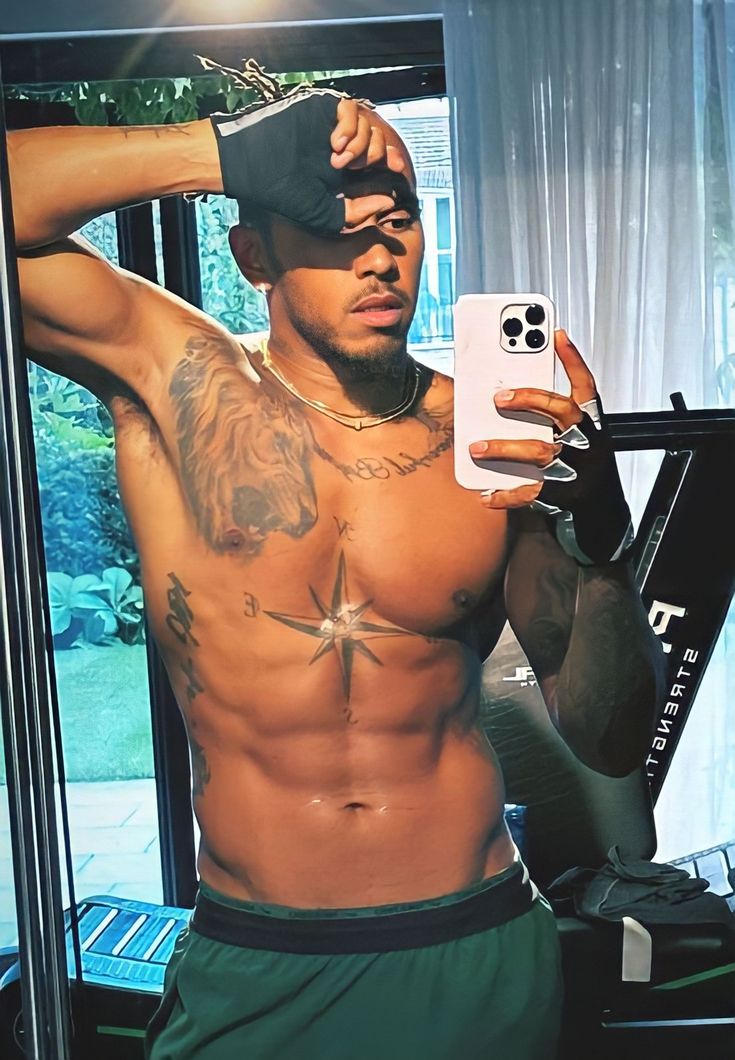 a shirtless man taking a selfie in front of a mirror with his cell phone