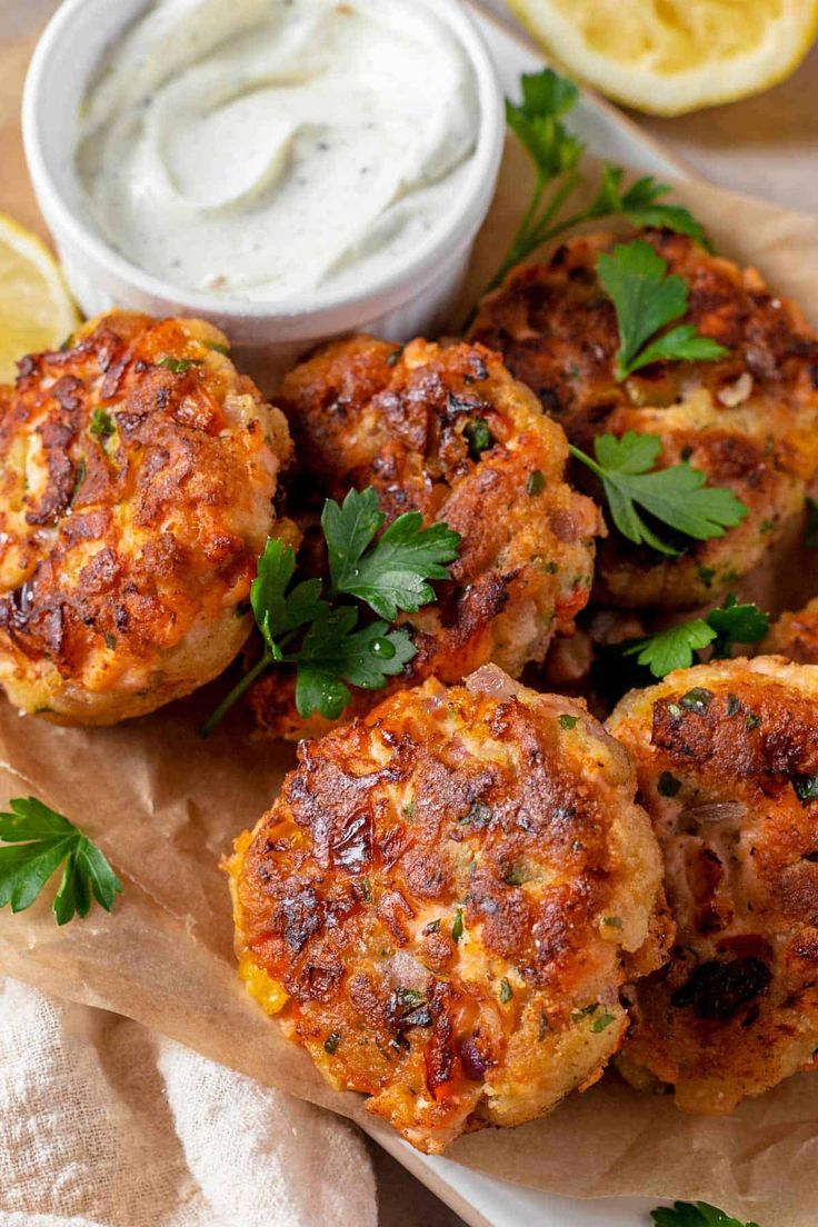 crab cakes with lemon wedges and parsley garnished with sour cream sauce