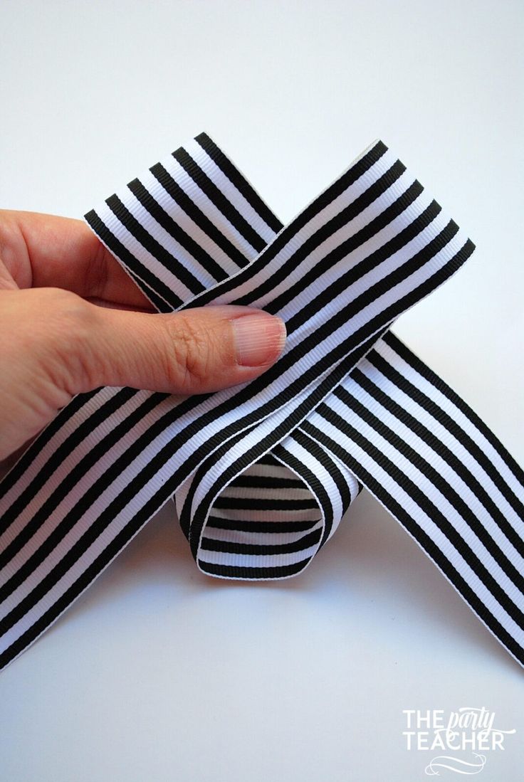 a hand holding a black and white striped ribbon