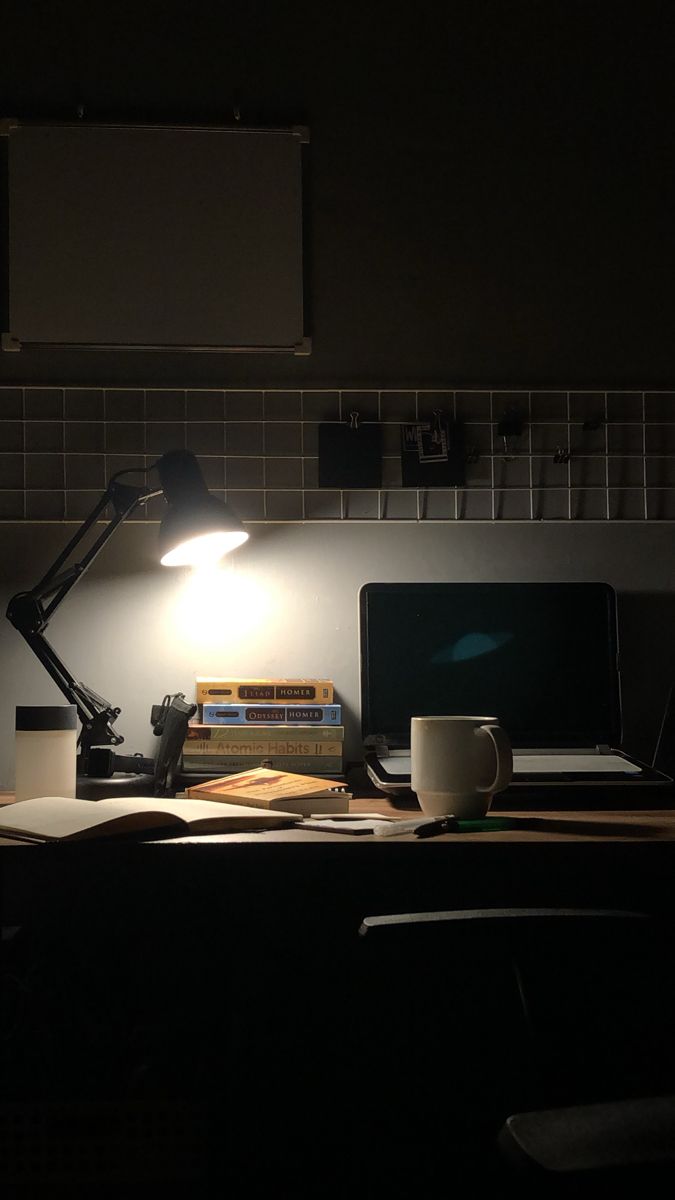 a desk with a laptop and a lamp on top of it in a dark room