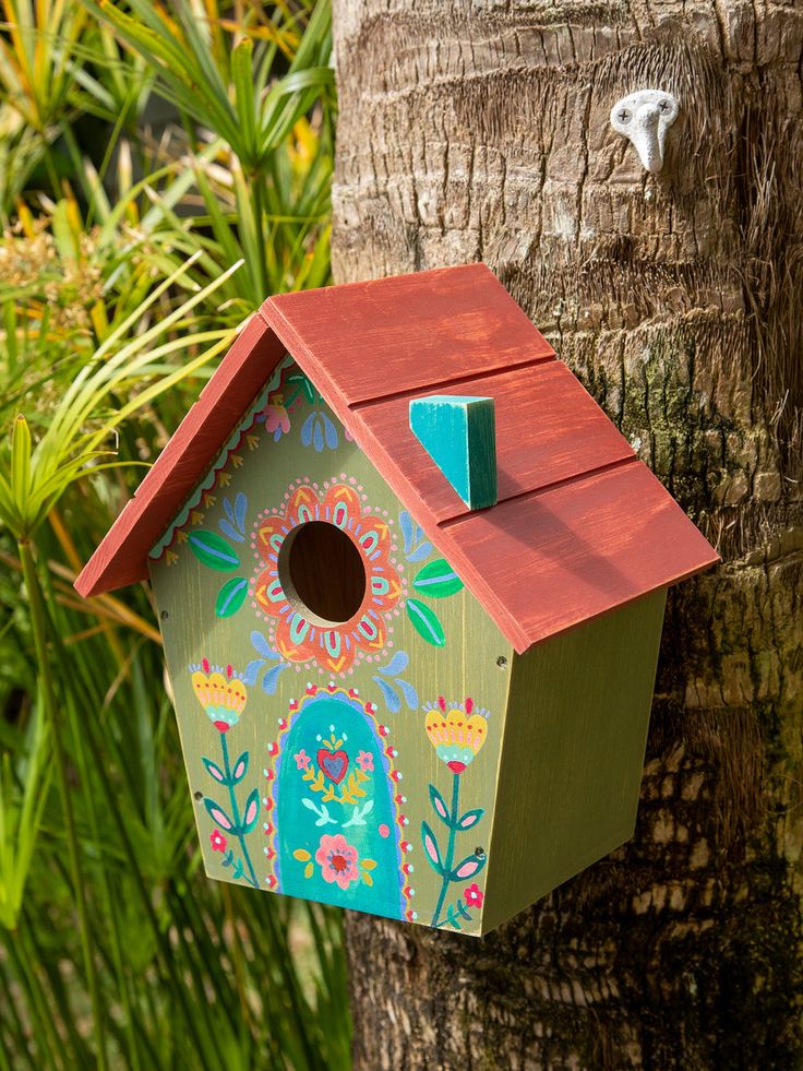 a colorful birdhouse is hanging on a tree