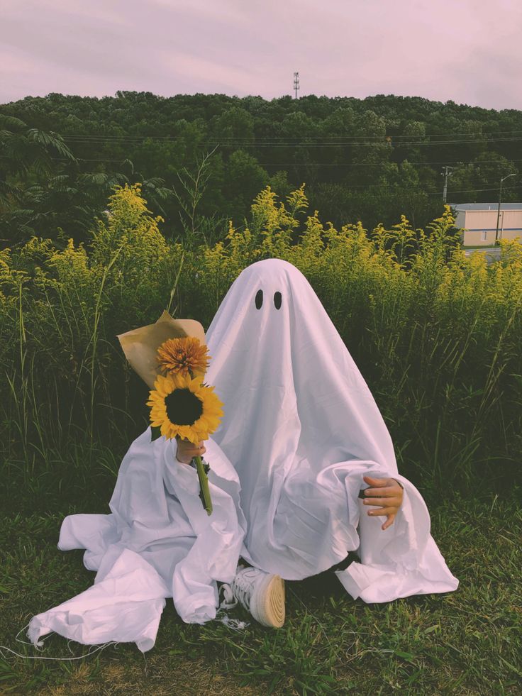 a person sitting in the grass with a sunflower on their head and a ghost behind them