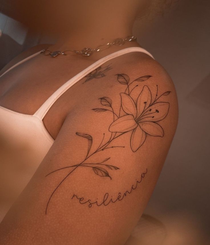 a woman's arm with a flower tattoo on the back of her left shoulder