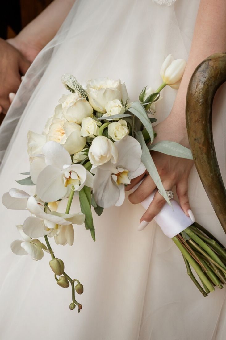 a bride holding a bouquet of white flowers in her hand and an antelope