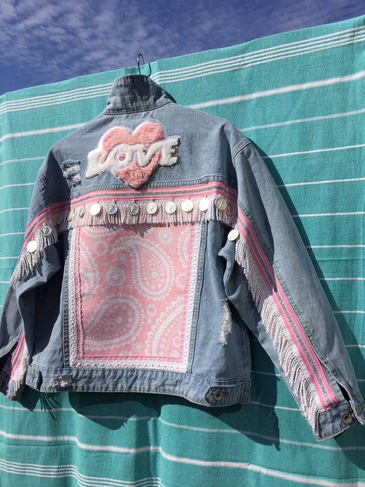 an old jean jacket is hanging on a towel with the word love painted on it