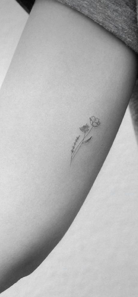 a woman's arm with a small flower tattoo on the left side of her right arm