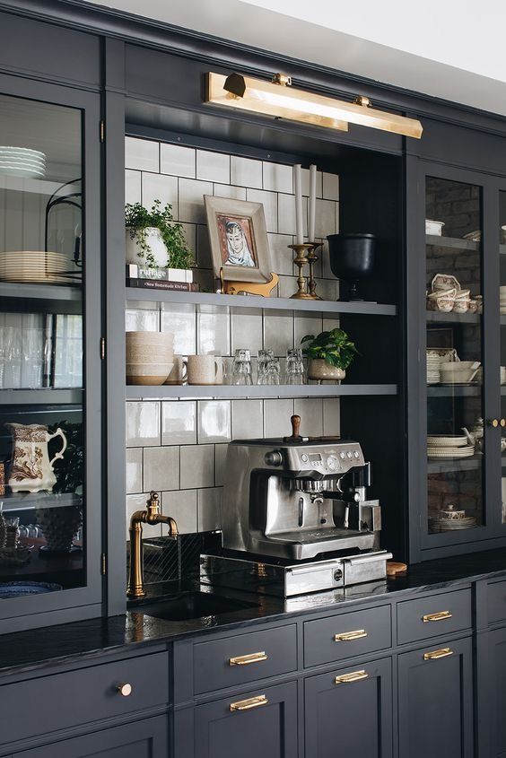 a kitchen with black cabinets and gold trim