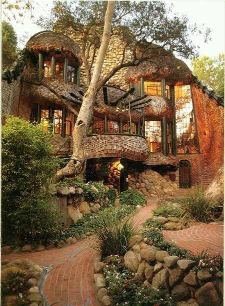 the house is made out of rocks and has trees growing on it's sides