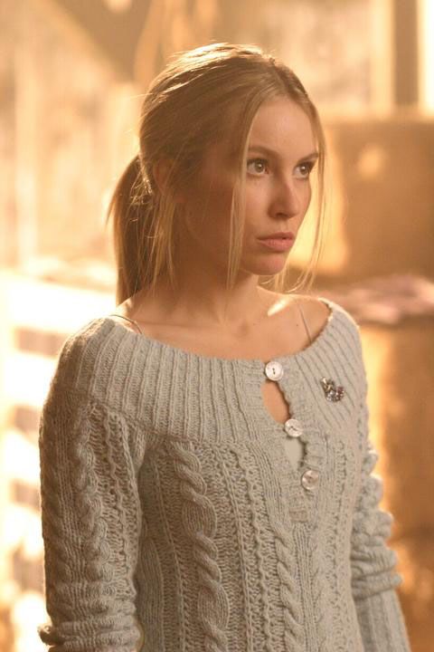 a woman in a white sweater looking at the camera