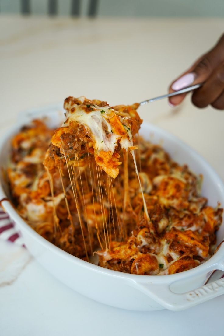 a person is holding a fork full of lasagna casserole with cheese