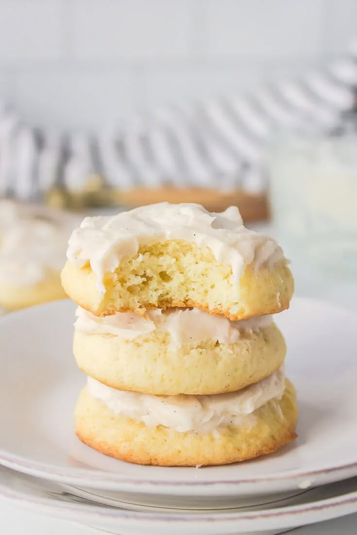 three frosted cookies stacked on top of each other with one bite taken out of it