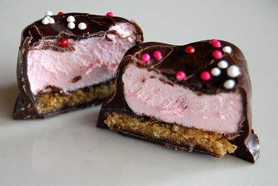 two pieces of chocolate with pink and white frosting on them sitting next to each other