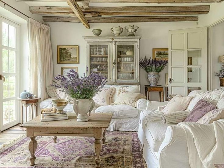 a living room filled with white furniture and lots of purple flowers on top of a rug