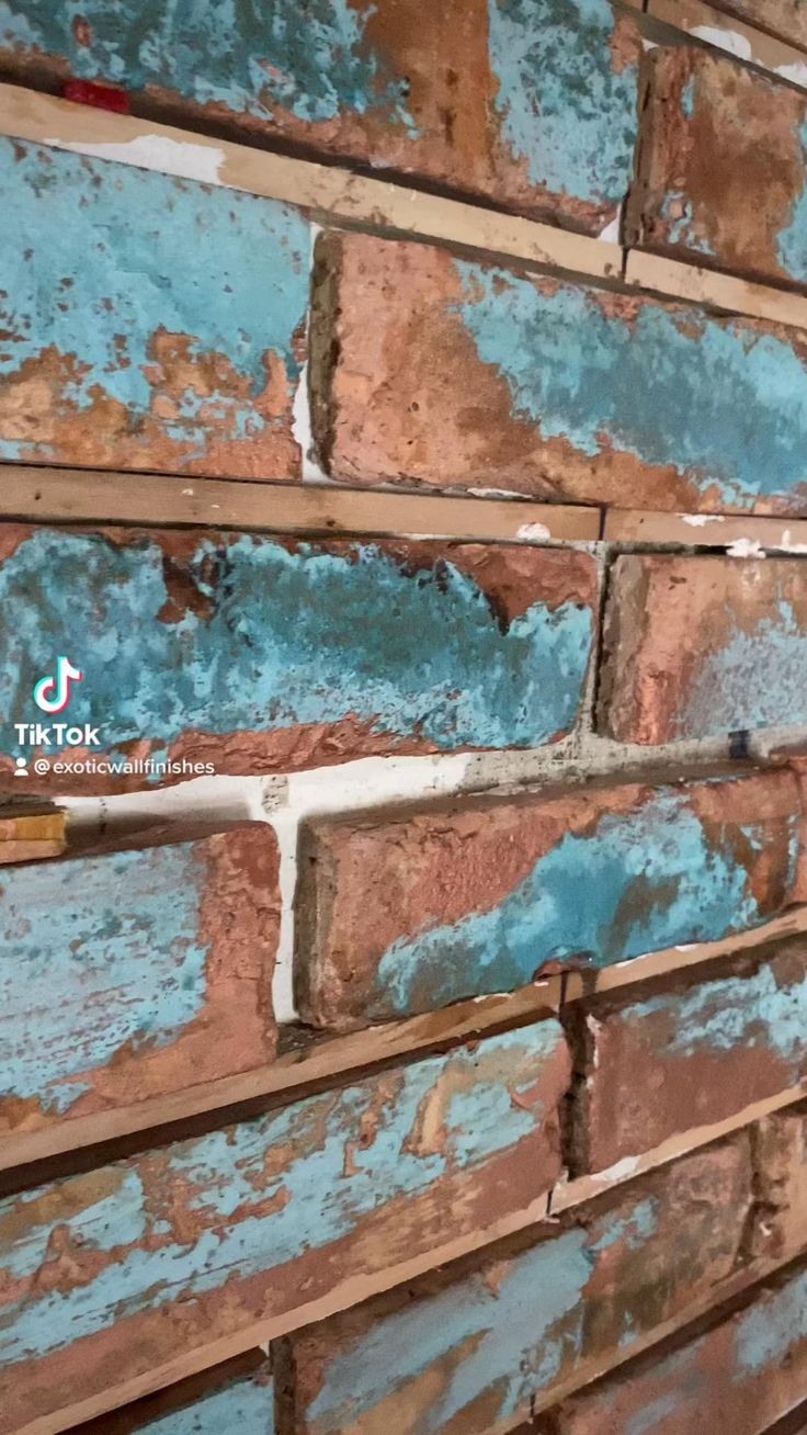 an old brick wall is painted blue and brown with rusted paint on the bricks