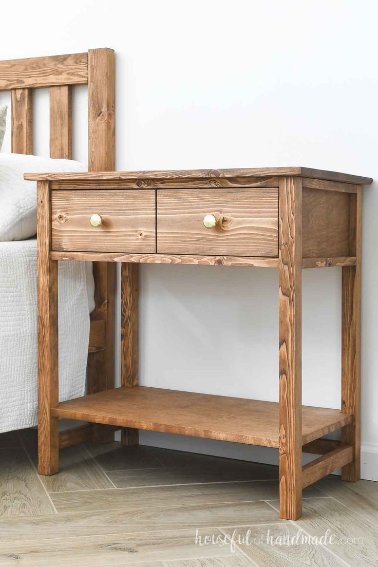 a wooden table with two drawers on top of it next to a bed and nightstand