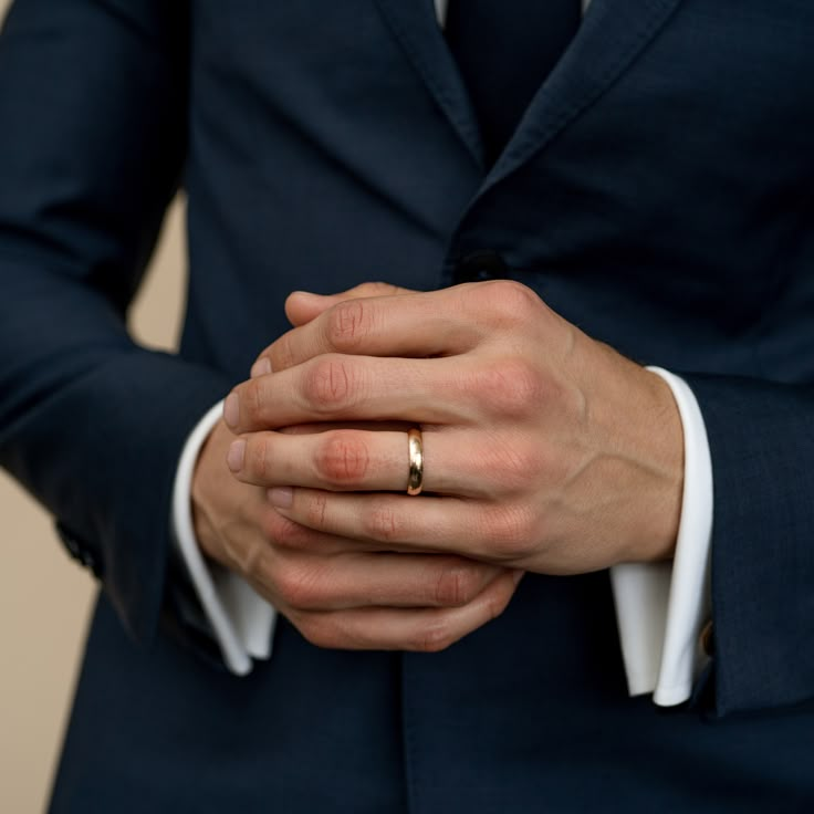 a man in a blue suit holding his hands together with the other hand on his chest