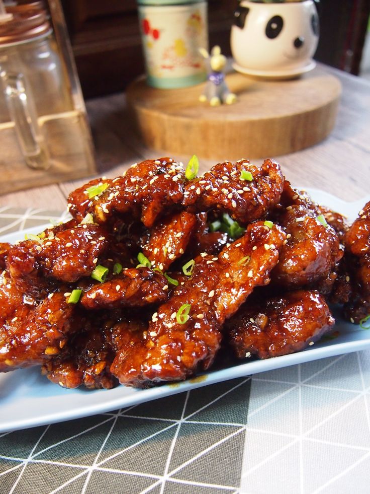 a white plate topped with chicken wings covered in sesame seeds