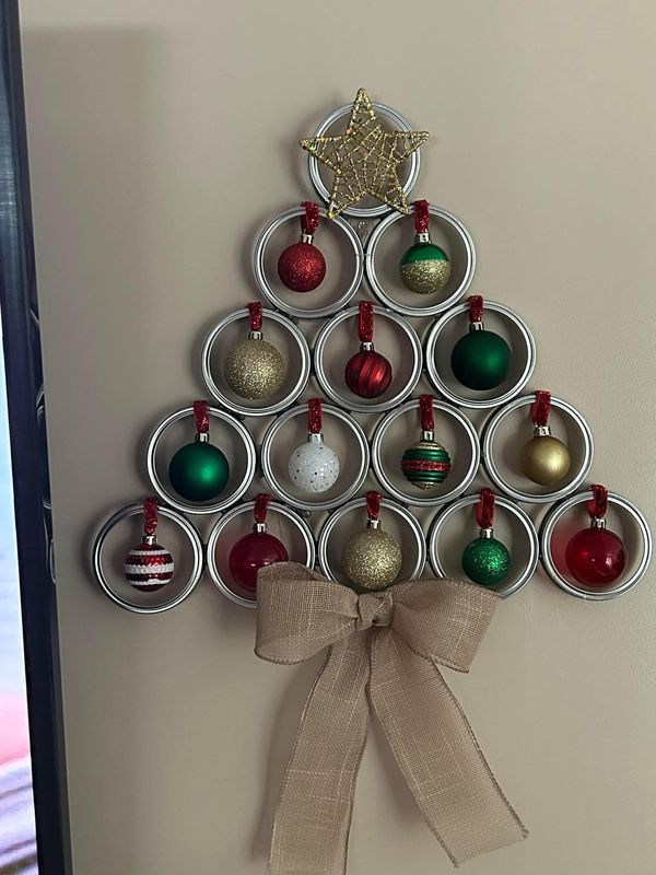 a christmas tree made out of cans with ornaments hanging from it's sides and a ribbon tied around the top