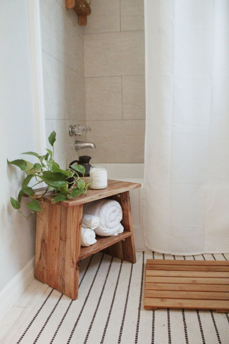 a bathroom with a wooden shelf and white towels on the floor next to a shower curtain