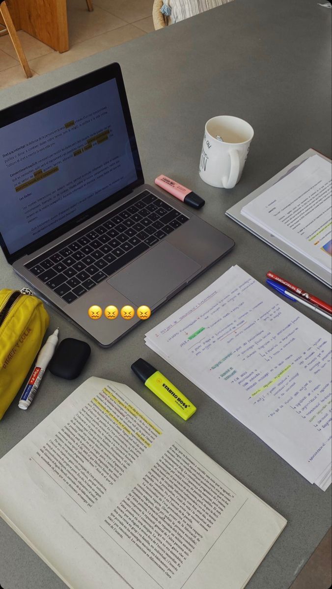 an open laptop computer sitting on top of a table next to notebooks and papers