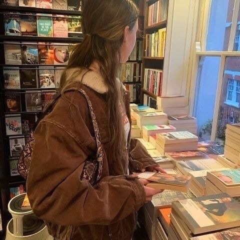 a woman standing in front of a bookshelf filled with lots of book's