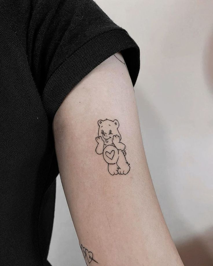 a small teddy bear tattoo on the right arm and left arm with an arrow in it