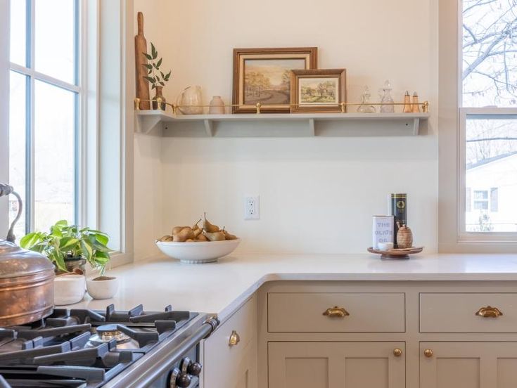 a kitchen with white counter tops and gold trim on the cabinets, along with an open window