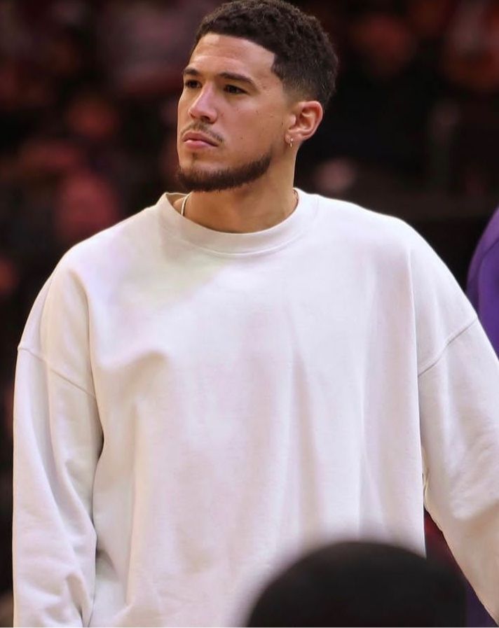 a man standing in front of a crowd wearing a white sweatshirt and looking off to the side