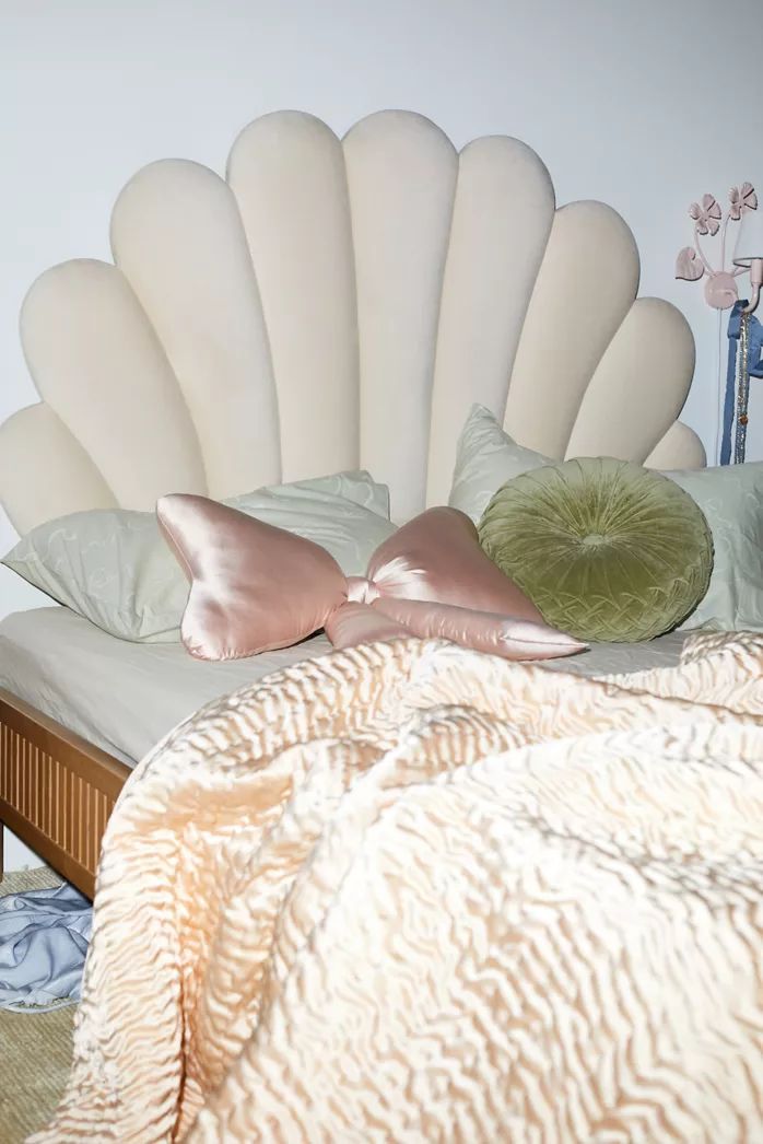 a bed with two pillows on top of it next to a white headboard and dresser