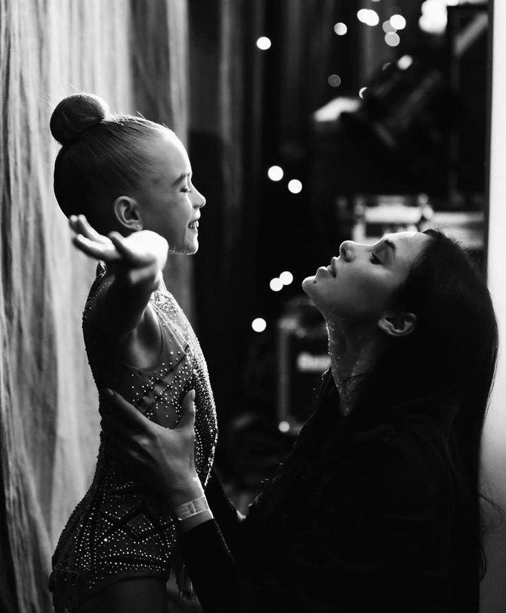 two women standing next to each other in front of a wall with lights on it