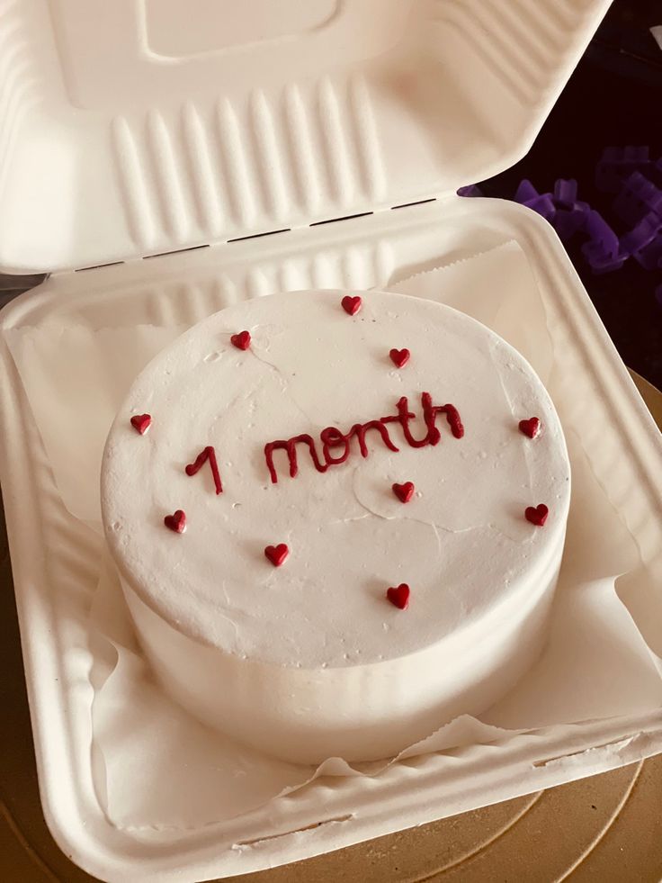 a white cake in a foam container with the word 1 month written on it and red hearts