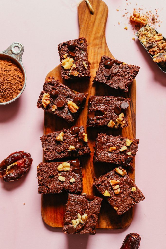 a wooden cutting board topped with brownies and nuts