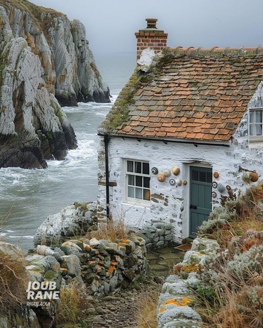 an old white house sitting on top of a cliff next to the ocean