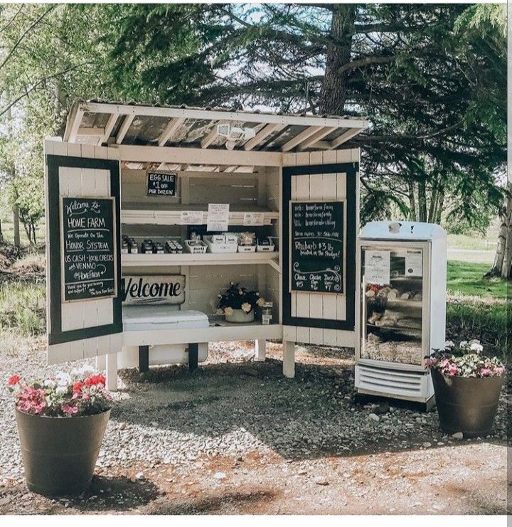 an outdoor food cart with chalkboard menus on the side and flowers in pots next to it