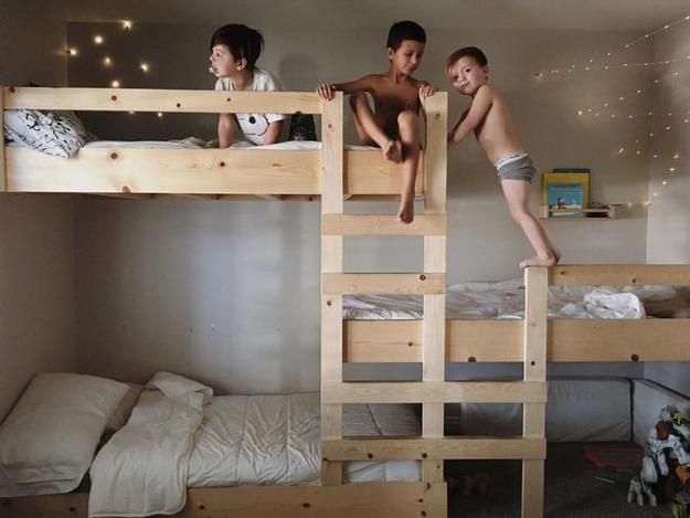 two boys are standing on top of bunk beds in a room with white walls and lights