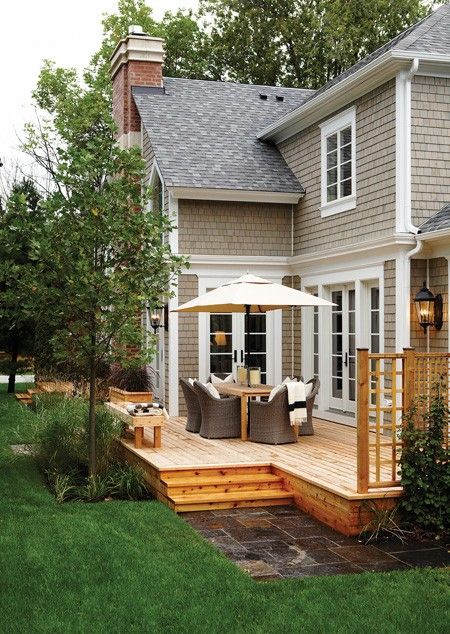 a deck with an umbrella on it in front of a house