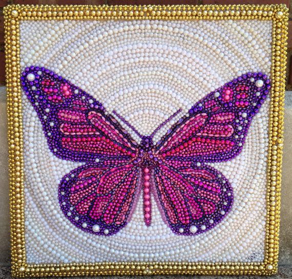 a pink butterfly on white and gold beaded fabric with beads in the shape of circles