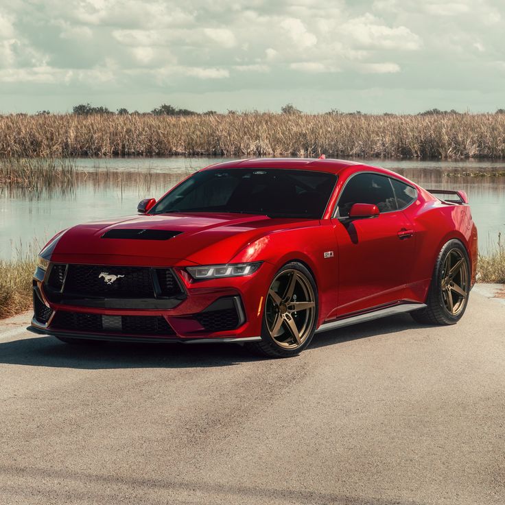 a red sports car parked in front of a body of water