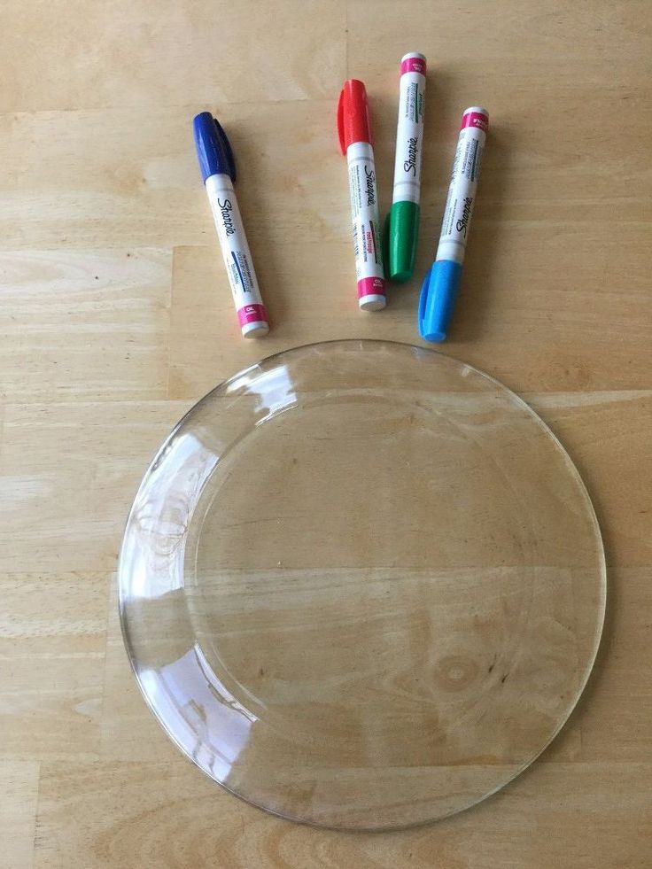 three markers are placed on top of a clear glass plate with four different colored pens