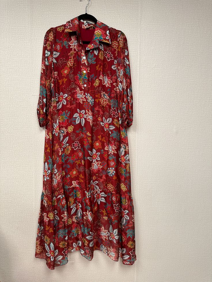 This Italian flower print satin midi dress is crafted from luxurious Italian satin, featuring a vibrant, elegant flower print and a loose fit silhouette. Exquisite details like long sleeves with elastic cuff and a ruffle bottom imbue the piece with a classic, sophisticated charm, while a four-button detail front collar adds a modern touch. Perfect for effortlessly elegant travel style. One Size. Long Sleeve Floral Print Maxi Dress, Silk Maxi Dress With Floral Print For Casual Occasions, Casual Silk Maxi Dress With Floral Print, Patterned Long Sleeve Printed Midi Dress, Flowy Silk Midi Dress With Floral Print, Red Silk Midi Dress With Floral Print, Casual Long Sleeve Silk Dress, Fall Silk Maxi Dress With Floral Print, Fall Floral Print Silk Maxi Dress