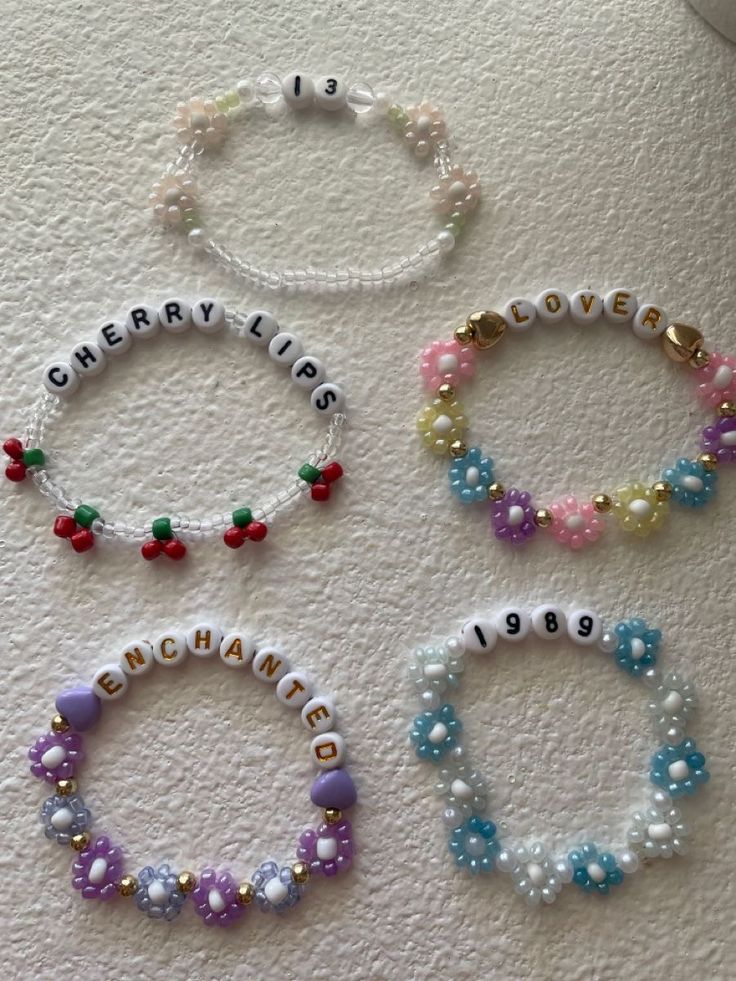 four bracelets with name charms on them sitting on a table next to each other