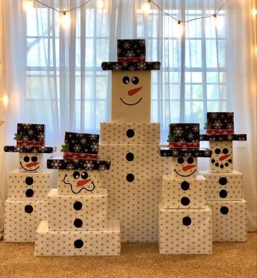 a group of snowmen made out of boxes and wrapped in polka dot paper with lights behind them