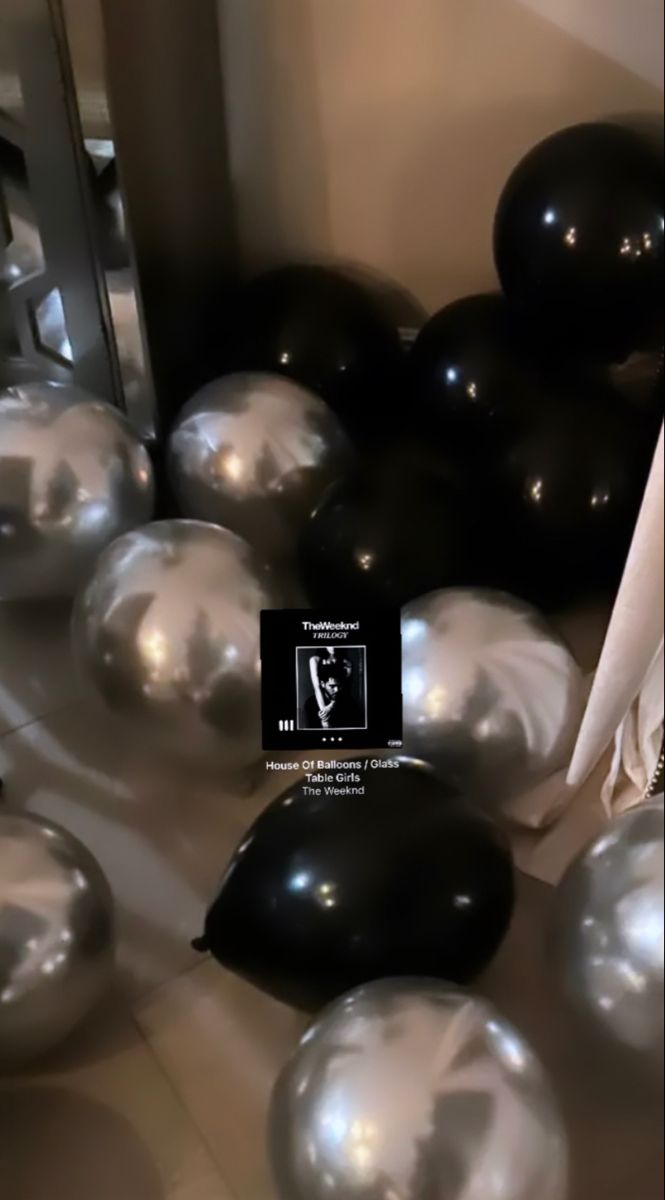 black and silver balloons are scattered around a mirror