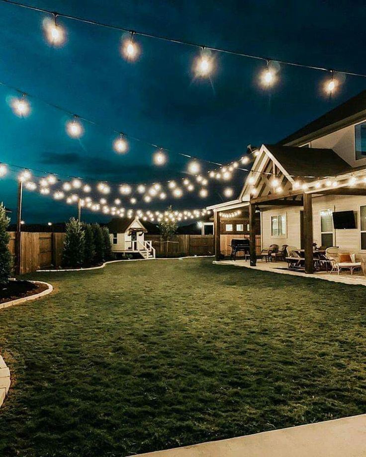 a backyard with lights strung over the grass