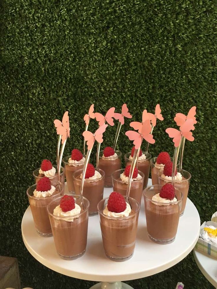 small desserts with strawberries and whipped cream on a white table in front of green grass