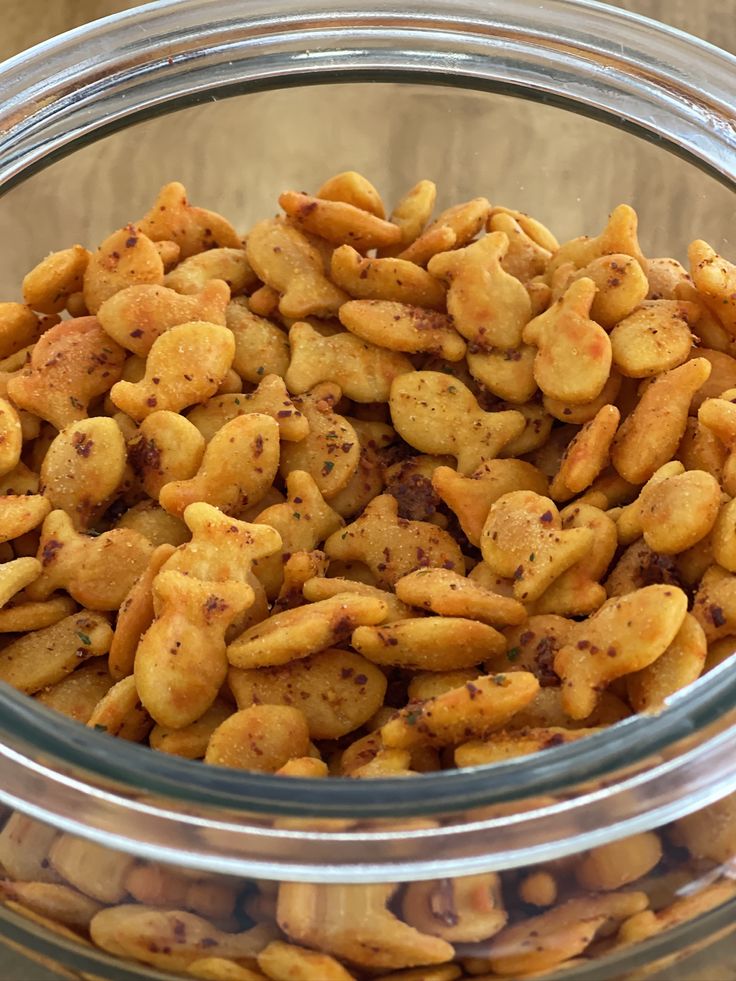 a glass bowl filled with nuts on top of a wooden table